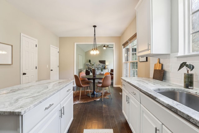 kitchen featuring dark wood-type flooring, pendant lighting, white cabinets, and tasteful backsplash