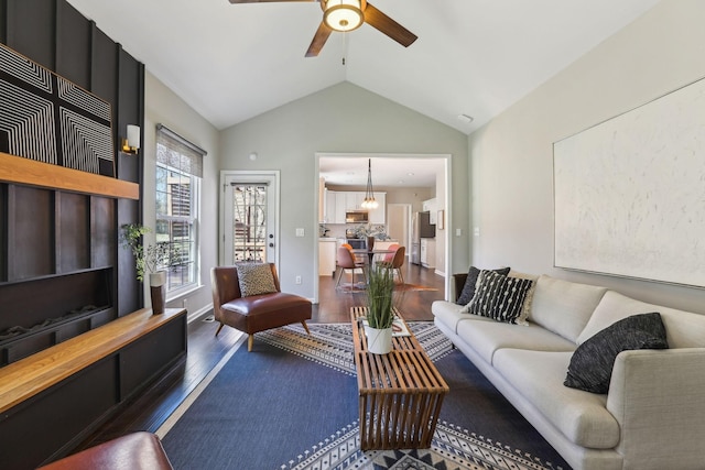 living area with lofted ceiling, ceiling fan, wood finished floors, and baseboards