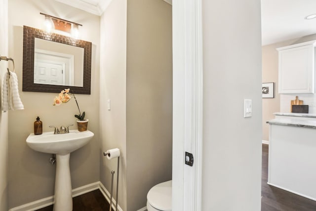 half bathroom featuring baseboards, toilet, and wood finished floors