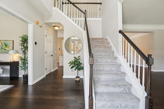 staircase with a high ceiling, baseboards, and hardwood / wood-style floors