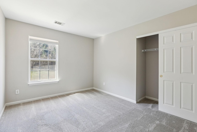 unfurnished bedroom with carpet floors, baseboards, visible vents, and a closet