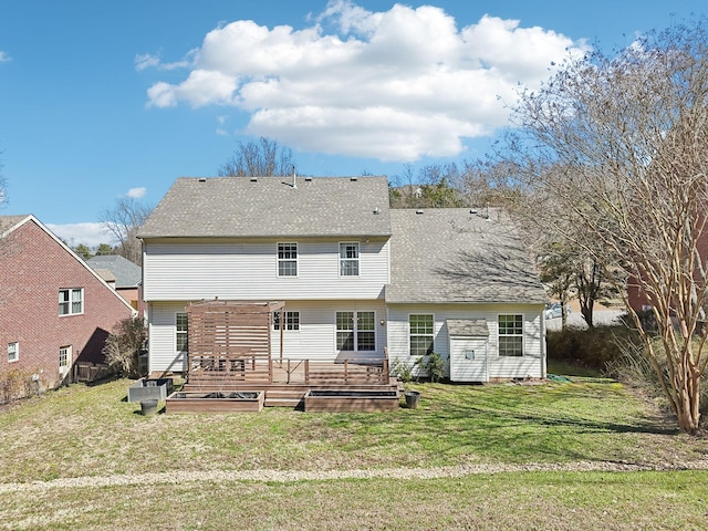 back of property featuring a deck, a lawn, and roof with shingles