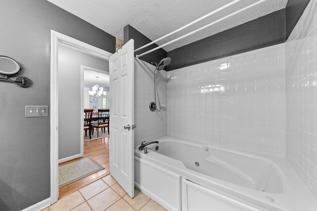 full bathroom featuring baseboards, bathing tub / shower combination, tile patterned floors, a textured ceiling, and a chandelier