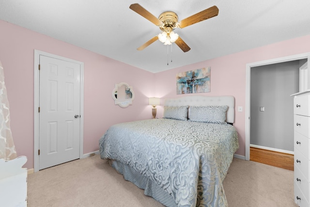 carpeted bedroom with ceiling fan and baseboards