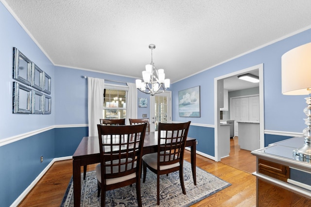 dining space with light wood-style floors, crown molding, baseboards, and a notable chandelier