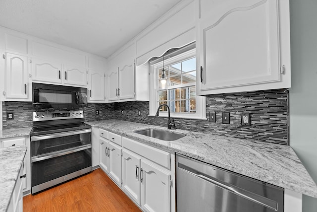 kitchen featuring light wood-type flooring, appliances with stainless steel finishes, white cabinets, and a sink