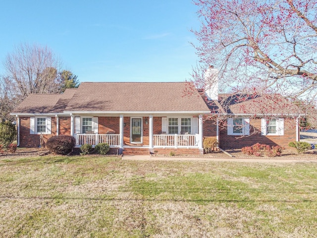 single story home with covered porch, a shingled roof, a front yard, and brick siding