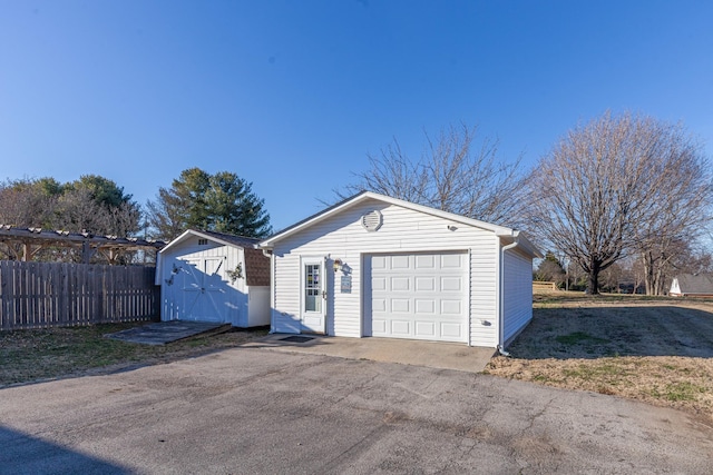 detached garage featuring fence and driveway