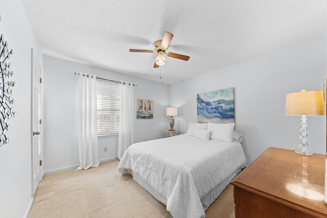 bedroom featuring light colored carpet, ceiling fan, a textured ceiling, and baseboards