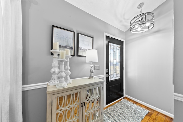 foyer featuring a notable chandelier, baseboards, and wood finished floors