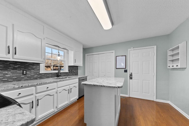 kitchen with decorative backsplash, dark wood-style floors, stainless steel dishwasher, white cabinetry, and a sink