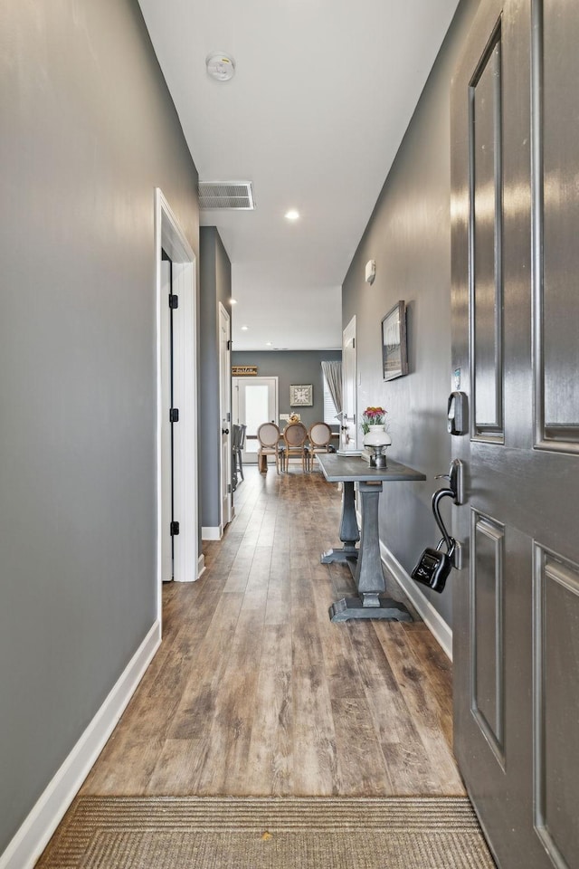 hall with recessed lighting, wood finished floors, visible vents, and baseboards