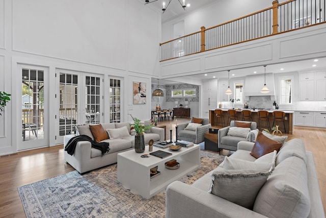 living room featuring french doors, light wood finished floors, a towering ceiling, and visible vents