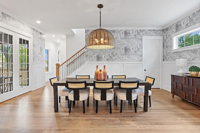 dining space featuring wallpapered walls, a notable chandelier, wood finished floors, and wainscoting