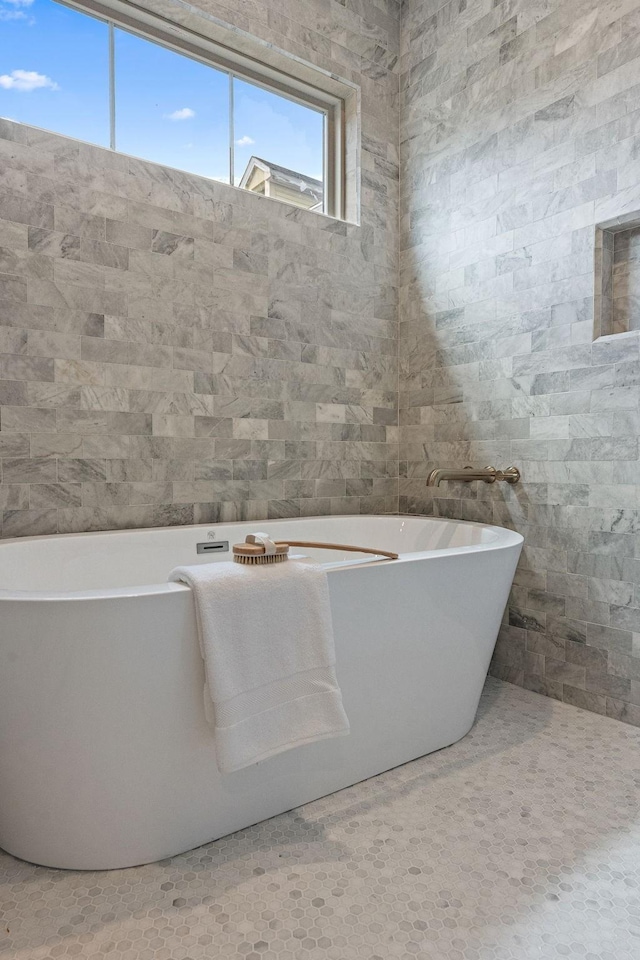 bathroom with a freestanding tub and tile walls