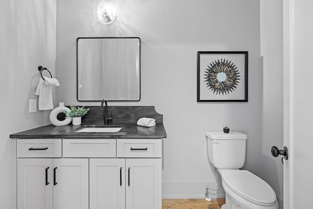 bathroom featuring wood finished floors, vanity, toilet, and baseboards