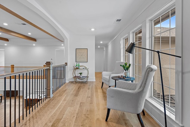 hall with beamed ceiling, wood finished floors, visible vents, and baseboards