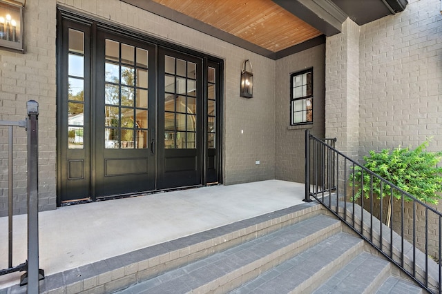 view of exterior entry featuring french doors and brick siding