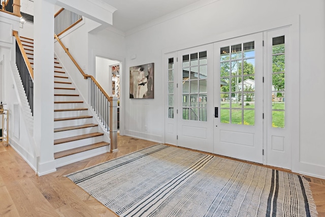 foyer entrance with baseboards, stairway, parquet floors, crown molding, and french doors