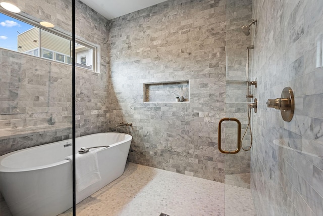 bathroom featuring a stall shower, a soaking tub, and tile walls