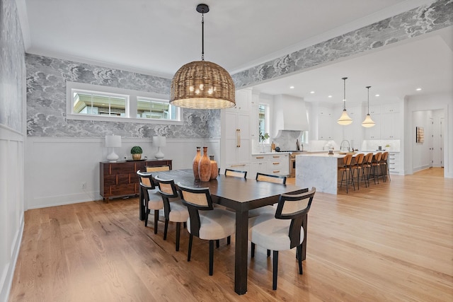 dining area with light wood-type flooring, a notable chandelier, crown molding, and recessed lighting