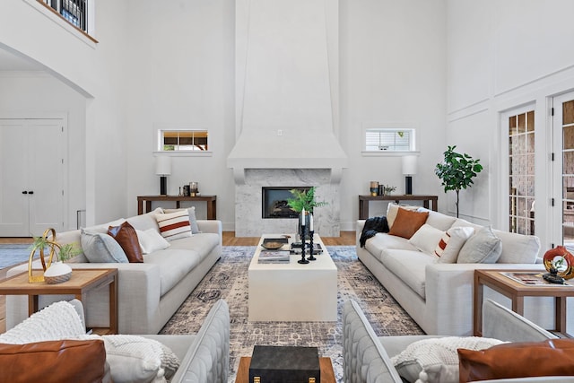 living room with a premium fireplace, a high ceiling, and wood finished floors