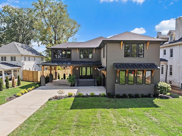 back of house featuring concrete driveway, a lawn, a standing seam roof, metal roof, and fence