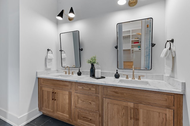 bathroom featuring double vanity, a sink, baseboards, and tile patterned floors