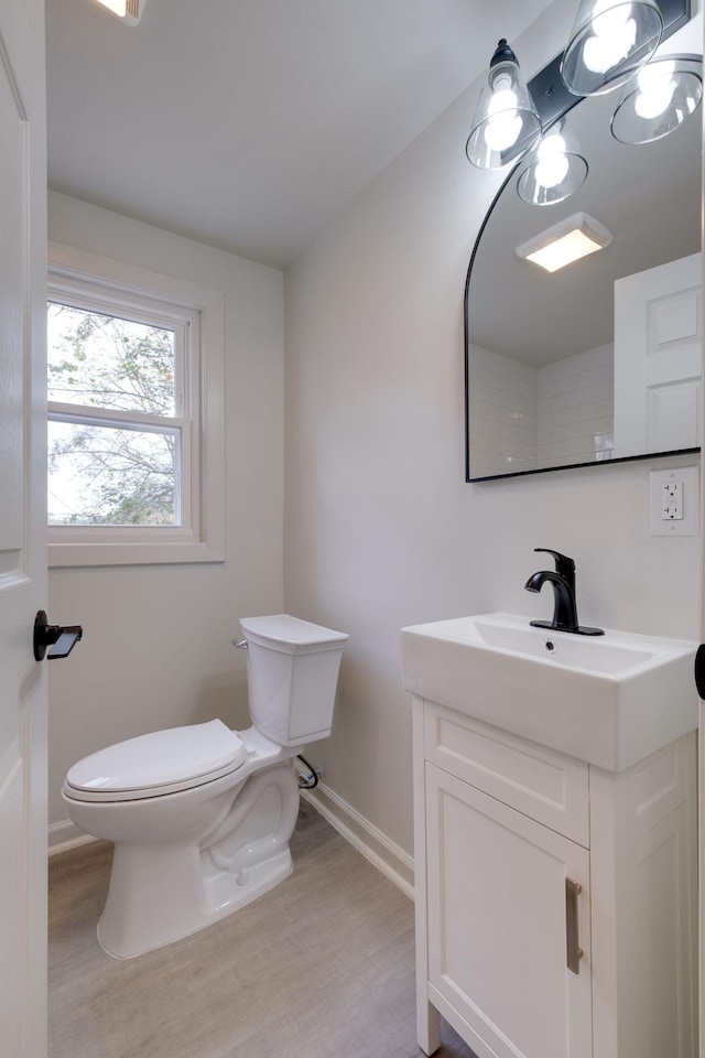 bathroom featuring wood finished floors, vanity, toilet, and baseboards