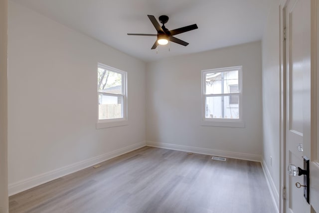 unfurnished room with visible vents, light wood finished floors, a ceiling fan, and baseboards