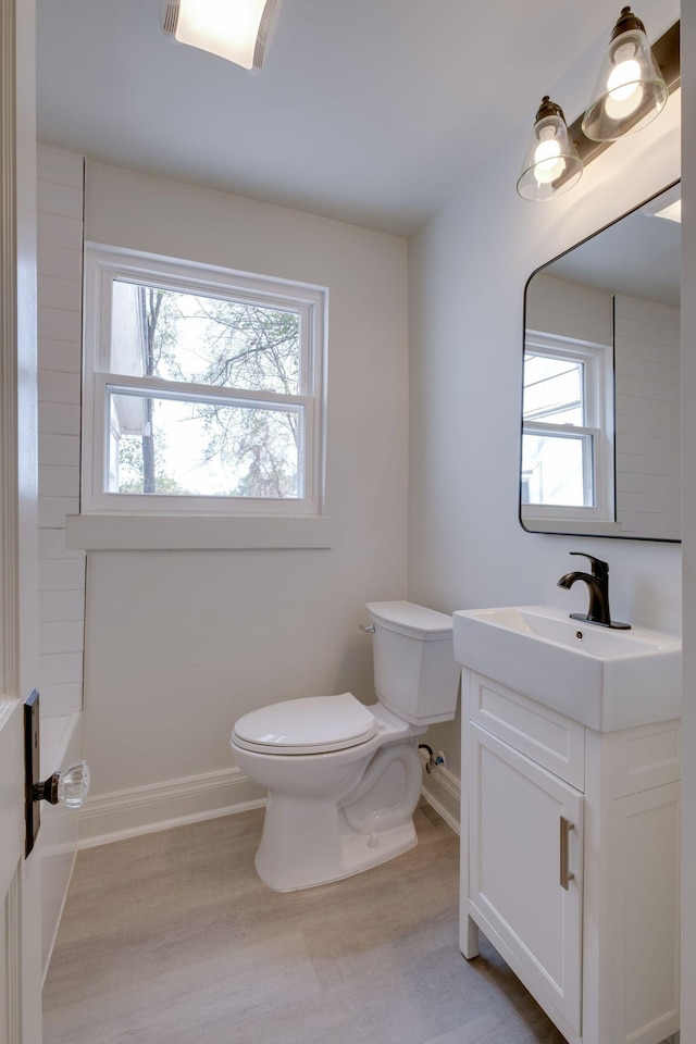 bathroom featuring baseboards, vanity, toilet, and wood finished floors