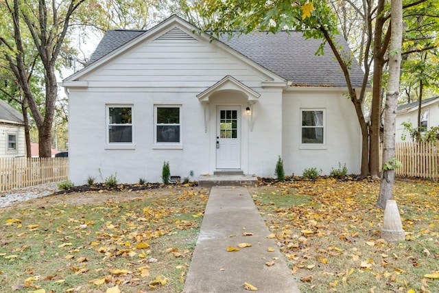 bungalow with a shingled roof and fence