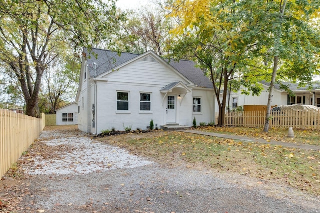 bungalow-style home featuring fence and roof with shingles