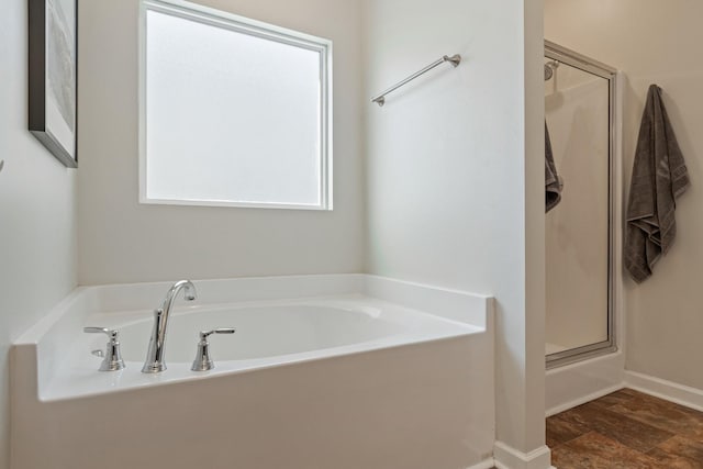 full bath with a wealth of natural light, baseboards, a garden tub, and a shower with door