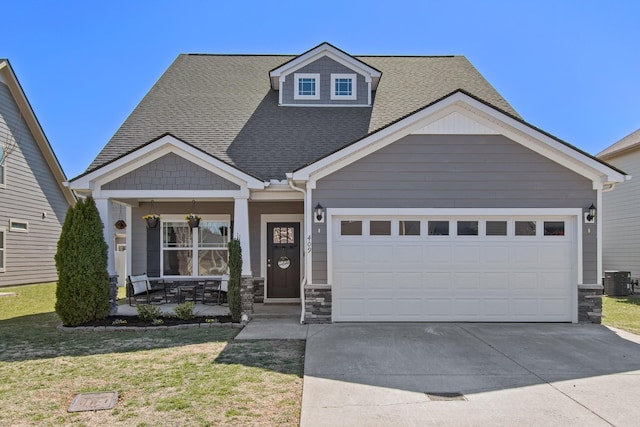 craftsman-style house with central air condition unit, a front lawn, driveway, stone siding, and a garage