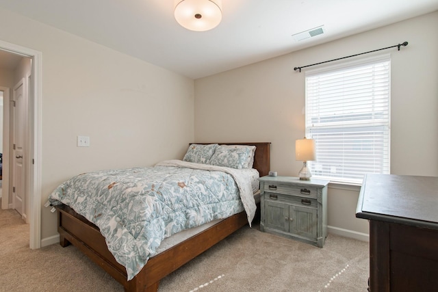 bedroom with baseboards, visible vents, and light carpet