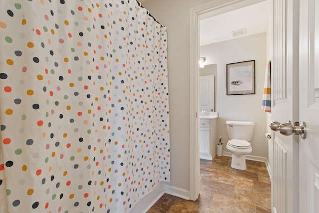 bathroom with visible vents, stone finish flooring, baseboards, toilet, and vanity