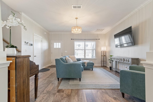 living area with visible vents, an inviting chandelier, wood finished floors, and crown molding