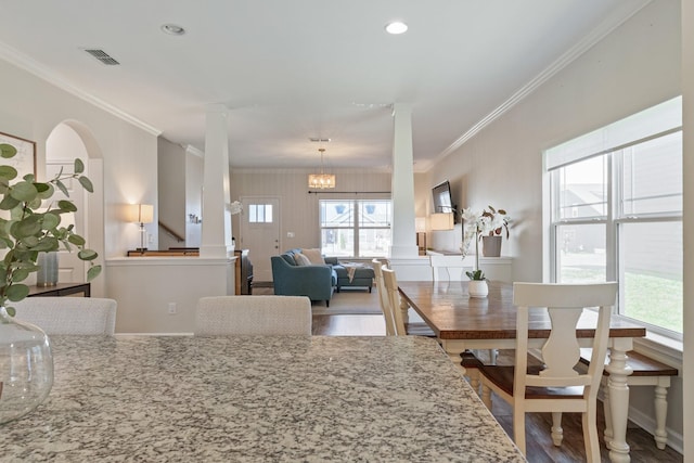 dining space with decorative columns, visible vents, wood finished floors, and ornamental molding