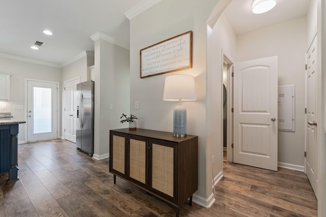 hallway with dark wood finished floors, visible vents, and ornamental molding