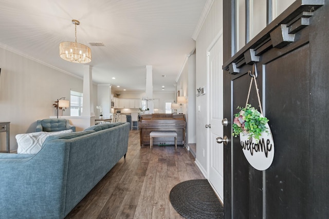 entrance foyer with dark wood-style floors, a notable chandelier, visible vents, and ornamental molding