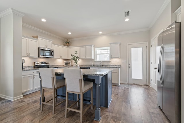 kitchen with a kitchen island, visible vents, white cabinetry, and stainless steel appliances