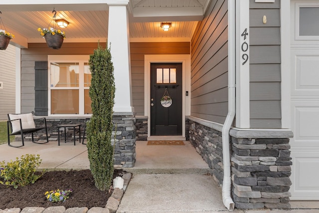 property entrance featuring a porch, a garage, and stone siding