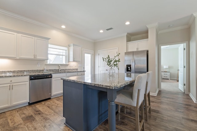 kitchen with white cabinetry, a kitchen breakfast bar, visible vents, and appliances with stainless steel finishes