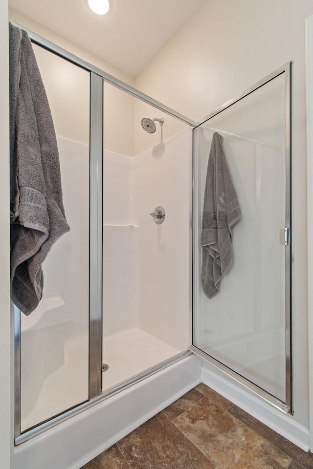 bathroom featuring a stall shower and stone finish flooring