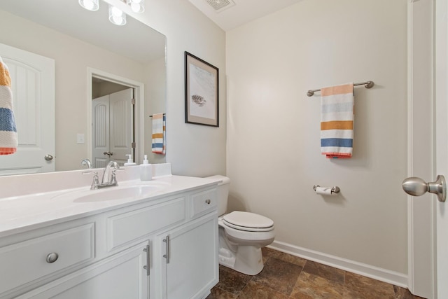 bathroom with visible vents, toilet, stone finish floor, baseboards, and vanity