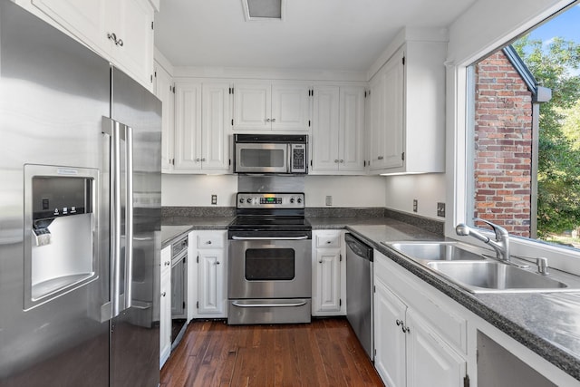 kitchen with dark wood finished floors, white cabinetry, stainless steel appliances, and a sink