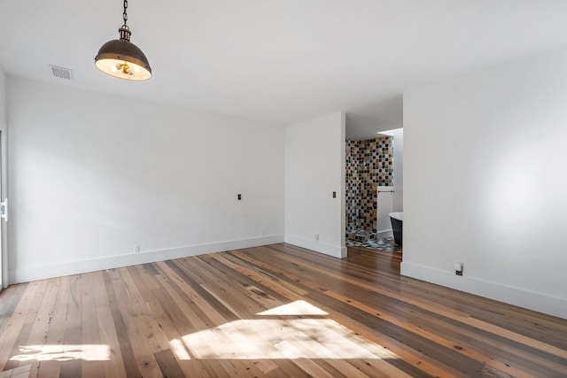 unfurnished room with wood-type flooring, visible vents, and baseboards