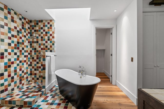 full bathroom with tiled shower, a freestanding bath, baseboards, and wood finished floors