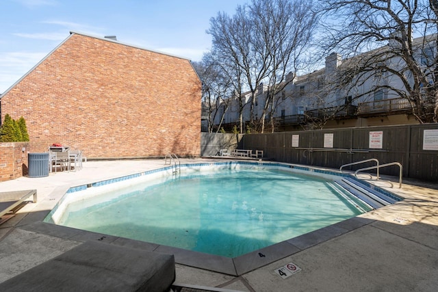 pool with a patio area and fence